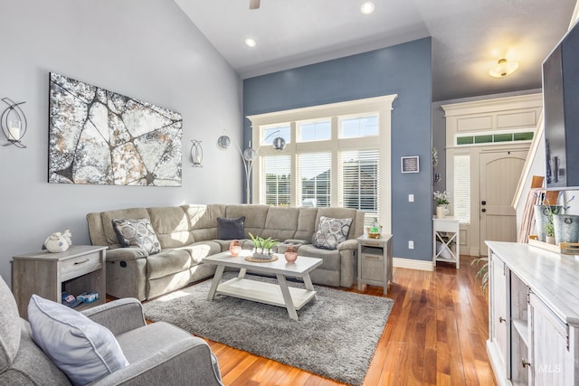 living room with recessed lighting, wood finished floors, a towering ceiling, and baseboards