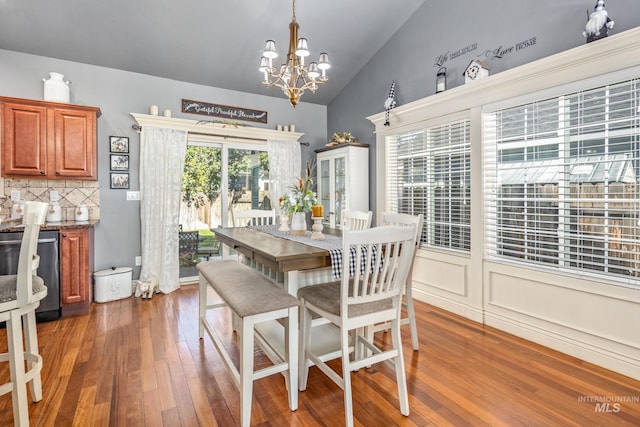 dining space featuring a notable chandelier, vaulted ceiling, and wood finished floors