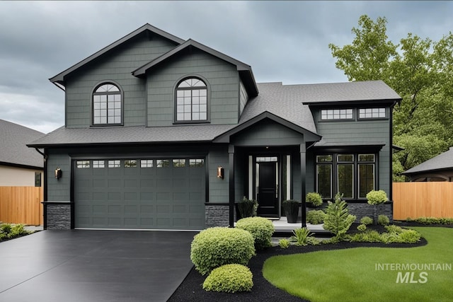 view of front of home featuring a garage, stone siding, fence, and driveway