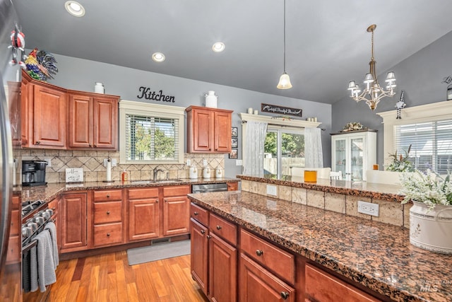 kitchen featuring a sink, vaulted ceiling, appliances with stainless steel finishes, light wood-type flooring, and decorative backsplash