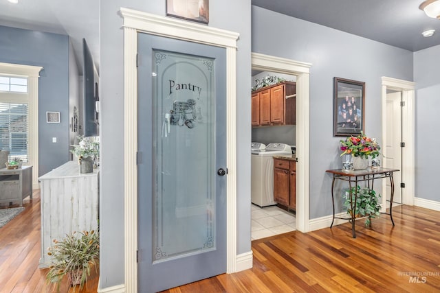 foyer featuring light wood-type flooring, baseboards, and separate washer and dryer