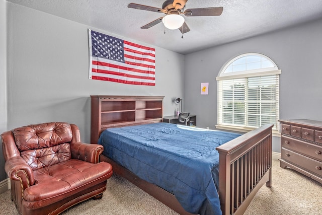 bedroom with light carpet, a ceiling fan, and a textured ceiling