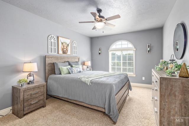 bedroom with light colored carpet, ceiling fan, a textured ceiling, and baseboards