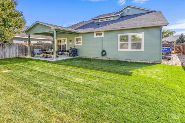 rear view of house with a yard, a fenced backyard, roof with shingles, and a patio