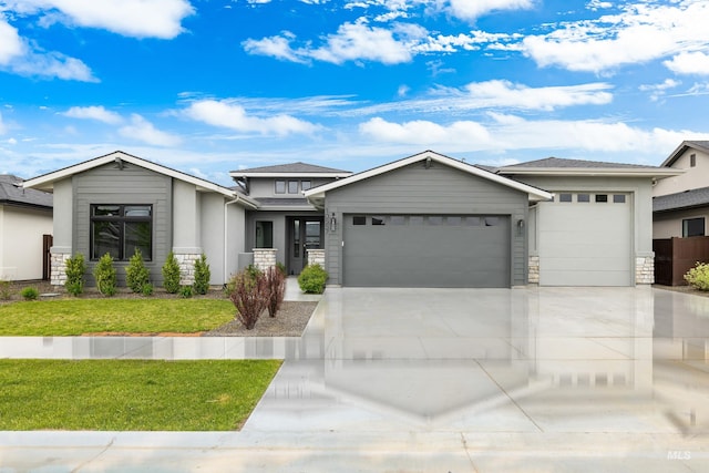 prairie-style house with an attached garage, a front yard, driveway, and stone siding