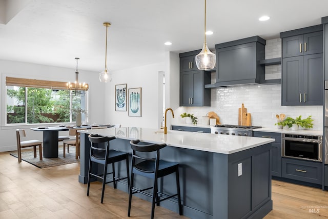 kitchen with light countertops, stainless steel appliances, decorative backsplash, and light wood-style flooring