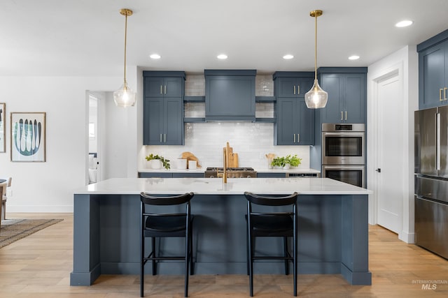 kitchen with light countertops, appliances with stainless steel finishes, backsplash, and a breakfast bar area