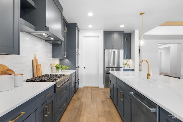 kitchen featuring backsplash, hanging light fixtures, a sink, light countertops, and stainless steel appliances