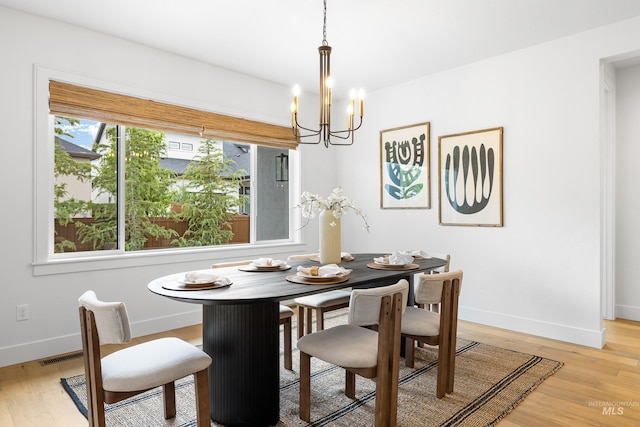 dining area featuring baseboards, a chandelier, light wood-style flooring, and visible vents