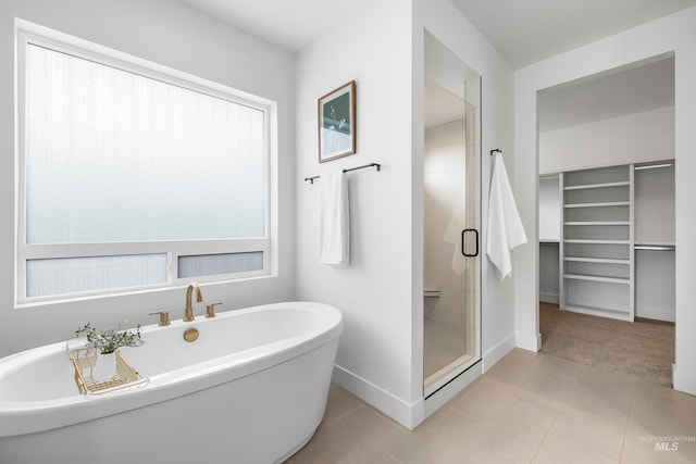 full bathroom featuring baseboards, a freestanding tub, and a stall shower