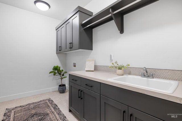 clothes washing area with washer hookup, cabinet space, a sink, baseboards, and light tile patterned floors