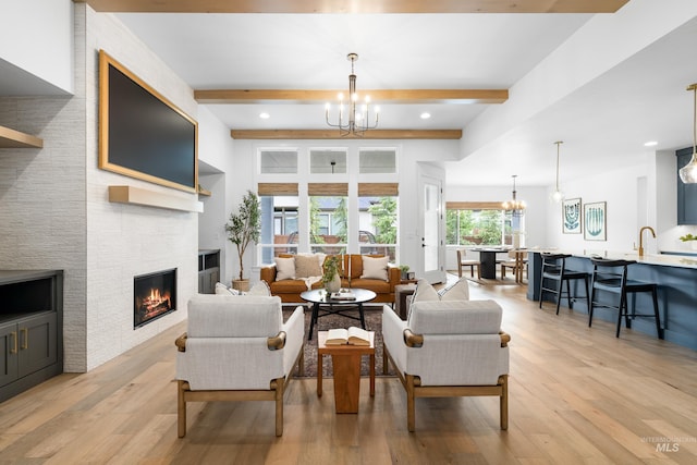 living area featuring light wood-style flooring, beam ceiling, and a notable chandelier