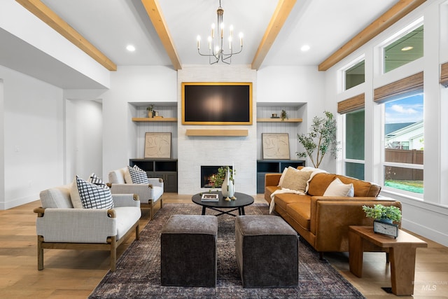 living area featuring a notable chandelier, beam ceiling, a fireplace, baseboards, and wood finished floors