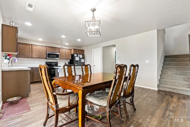 dining space with light wood finished floors, recessed lighting, stairs, a chandelier, and baseboards