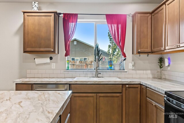 kitchen featuring brown cabinetry, light stone counters, black electric range, dishwasher, and decorative backsplash