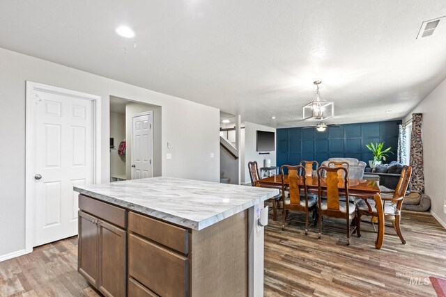kitchen with wood finished floors, a center island, light countertops, and baseboards