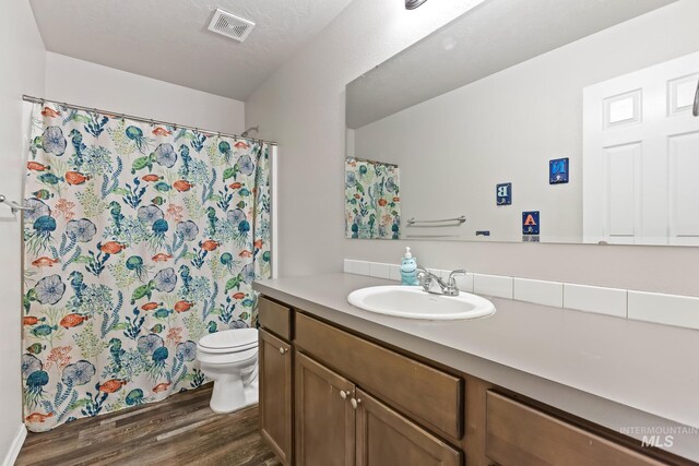 bathroom featuring wood finished floors, toilet, vanity, and curtained shower