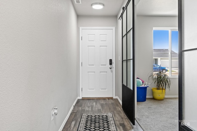doorway to outside with dark wood finished floors, baseboards, and a barn door