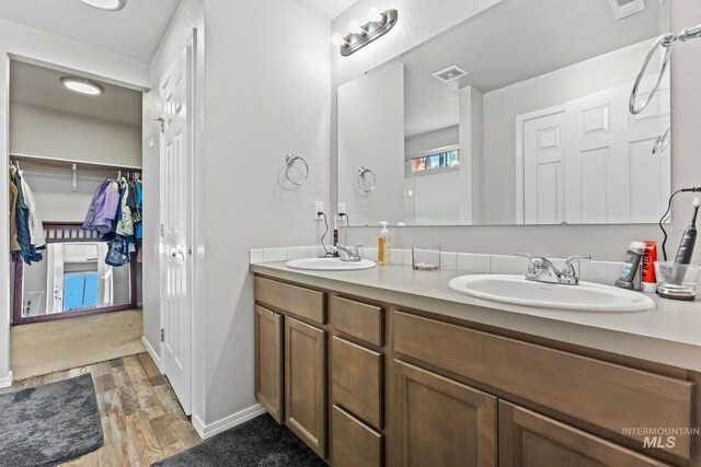 bathroom featuring wood finished floors, double vanity, and a spacious closet