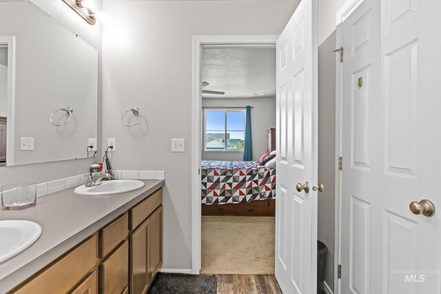 bathroom with ensuite bath, wood finished floors, double vanity, and baseboards