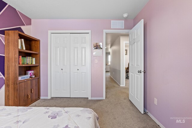 carpeted bedroom with a closet and baseboards