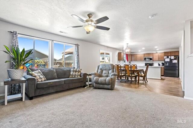 living room with light colored carpet, a ceiling fan, a textured ceiling, baseboards, and recessed lighting