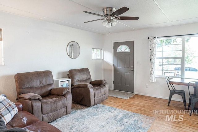 living room with wood finished floors, baseboards, and ceiling fan