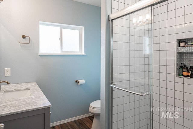 full bathroom featuring vanity, toilet, wood finished floors, and a stall shower