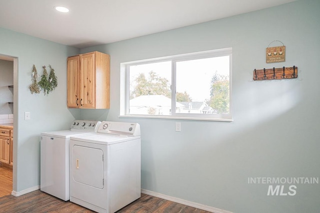 washroom with dark wood-style floors, washing machine and dryer, cabinet space, and baseboards