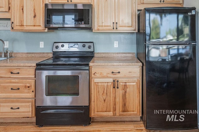 kitchen featuring light brown cabinetry, stainless steel appliances, and light countertops