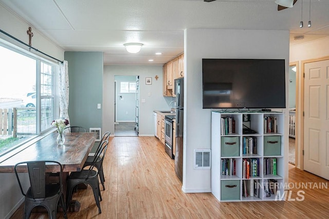 kitchen featuring visible vents, baseboards, light wood-type flooring, stainless steel range with electric stovetop, and a sink