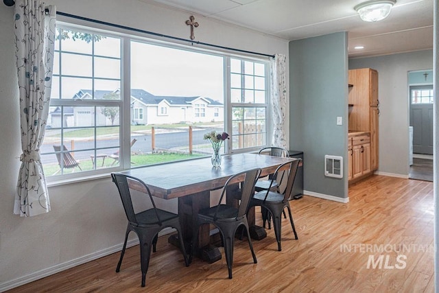 dining space featuring light wood finished floors, plenty of natural light, heating unit, and baseboards