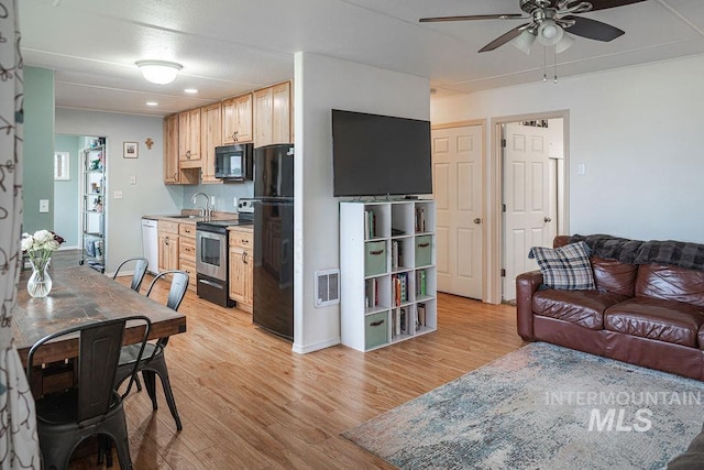 kitchen featuring visible vents, light brown cabinetry, a sink, black appliances, and light wood-type flooring