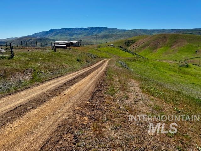 view of dirt / gravel road featuring a view of rural / pastoral area and a mountain view