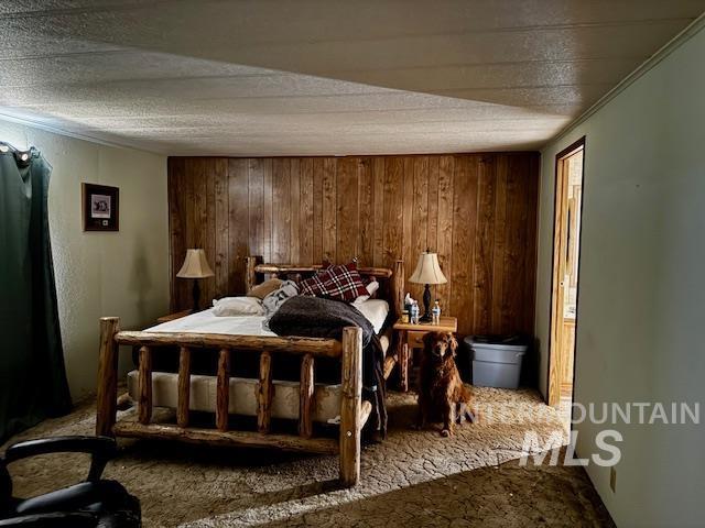 carpeted bedroom featuring wooden walls and ornamental molding