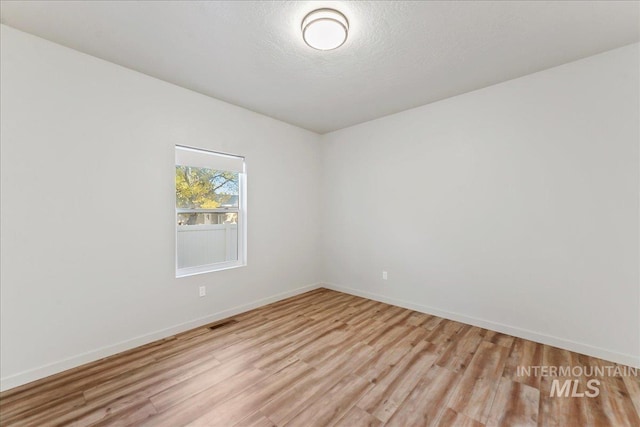 empty room featuring a textured ceiling and light wood-type flooring