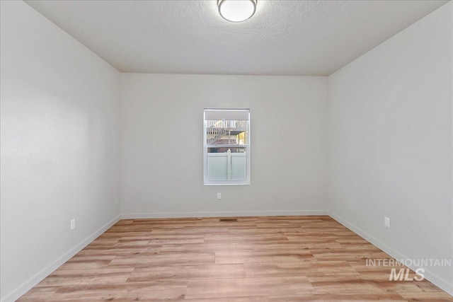 spare room with light hardwood / wood-style floors and a textured ceiling