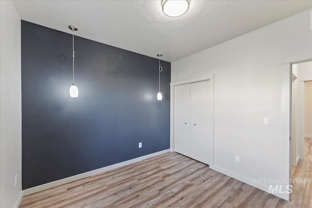 unfurnished bedroom featuring a closet, a textured ceiling, and light hardwood / wood-style flooring