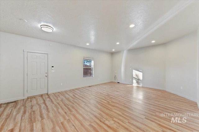 spare room with light hardwood / wood-style floors and a textured ceiling