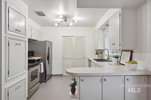 kitchen featuring a sink, stainless steel appliances, light countertops, a peninsula, and white cabinets