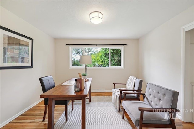 office area featuring light wood-type flooring, a baseboard heating unit, and baseboards