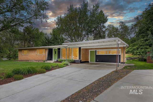 view of front of home with a yard, concrete driveway, and brick siding