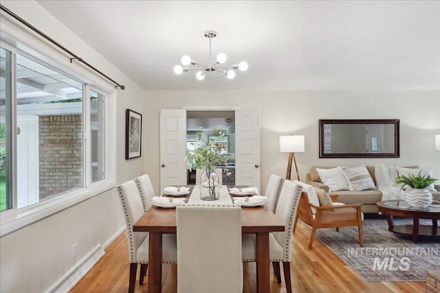 dining space with a chandelier, light wood-type flooring, a baseboard heating unit, and baseboards