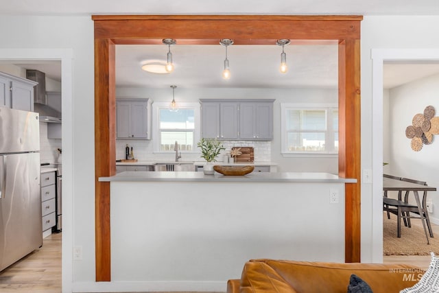 3716 W Palouse St, Boise, ID 83705 - kitchen with appliances with stainless steel finishes, gray cabinetry, decorative backsplash, wall chimney range hood, and light countertops