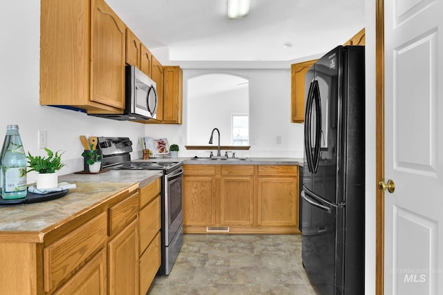 kitchen with stainless steel microwave, visible vents, freestanding refrigerator, electric stove, and a sink