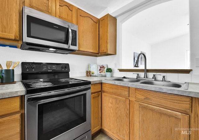 kitchen featuring a sink, stainless steel appliances, brown cabinets, and light countertops