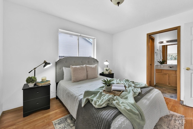 bedroom featuring baseboards, multiple windows, ensuite bathroom, and light wood finished floors