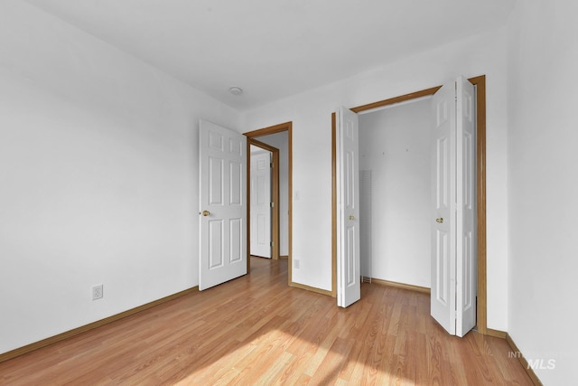 unfurnished bedroom featuring a closet, light wood-style flooring, and baseboards