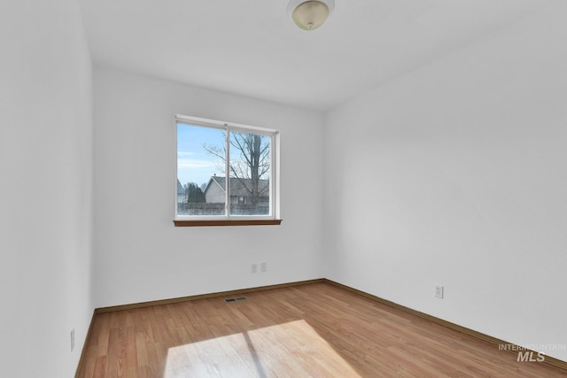 spare room with visible vents, wood finished floors, and baseboards