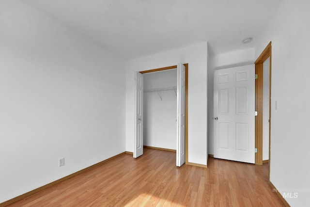 unfurnished bedroom with a closet, baseboards, and light wood-style floors